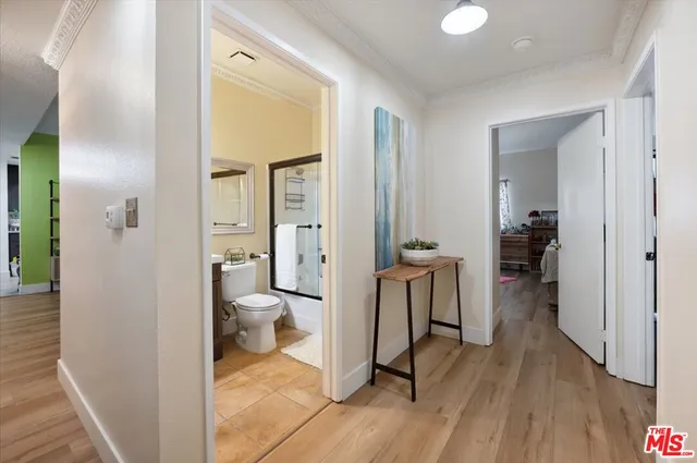 a view of a hallway with bathroom and wooden floor