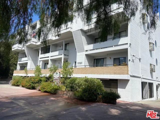 a white building with a large window and potted plants