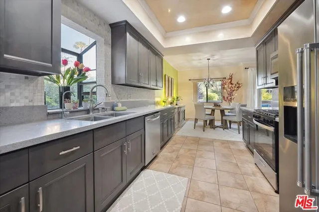 a large kitchen with stainless steel appliances granite countertop a sink counter space cabinets and a potted plant