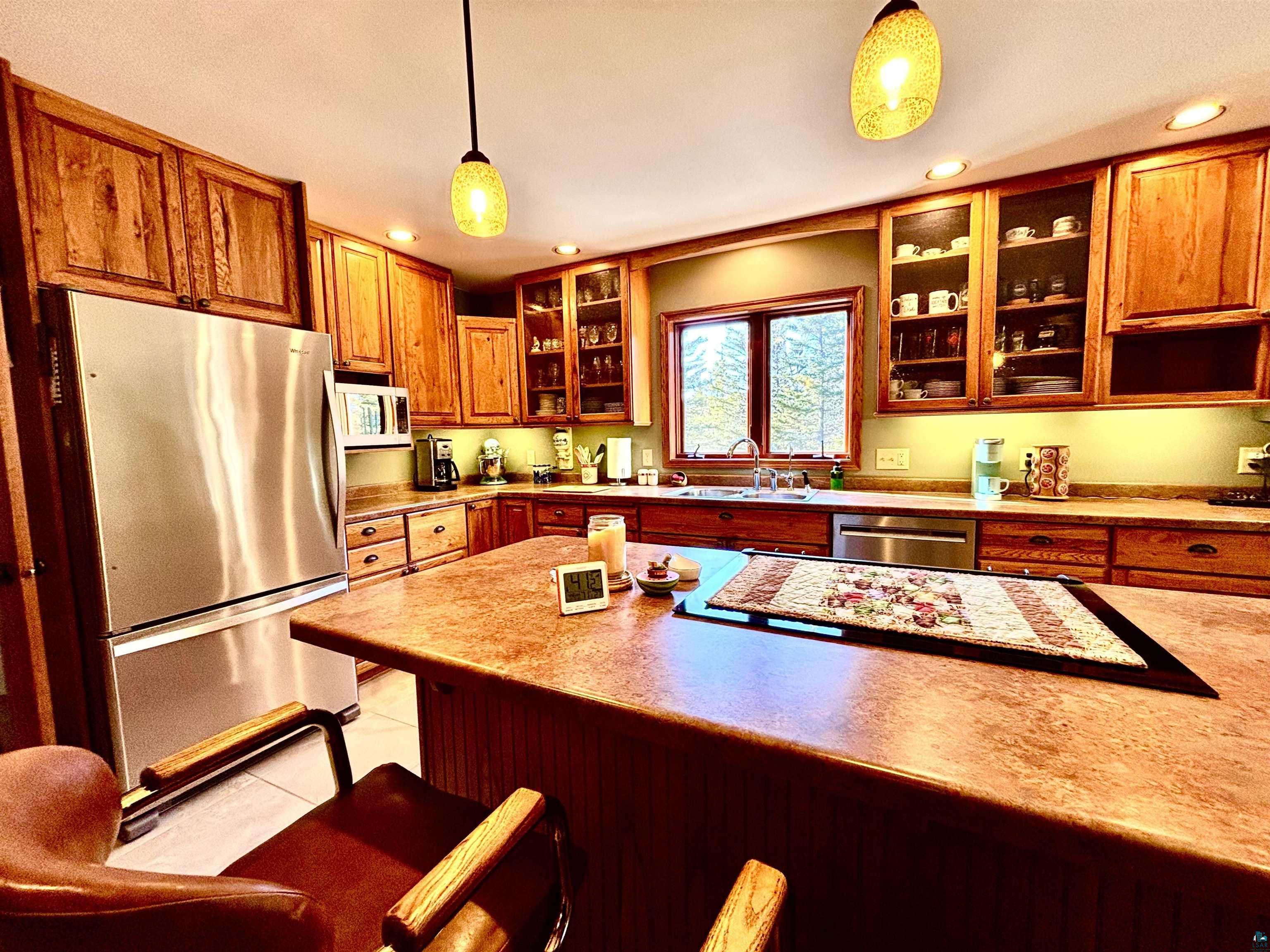 21 Turnagain Trail Lutsen, MN 55612 - Photo 16 of 77 Kitchen featuring wood cabinetry, stainless steel appliances, a center island with seating, and a window above the sink
