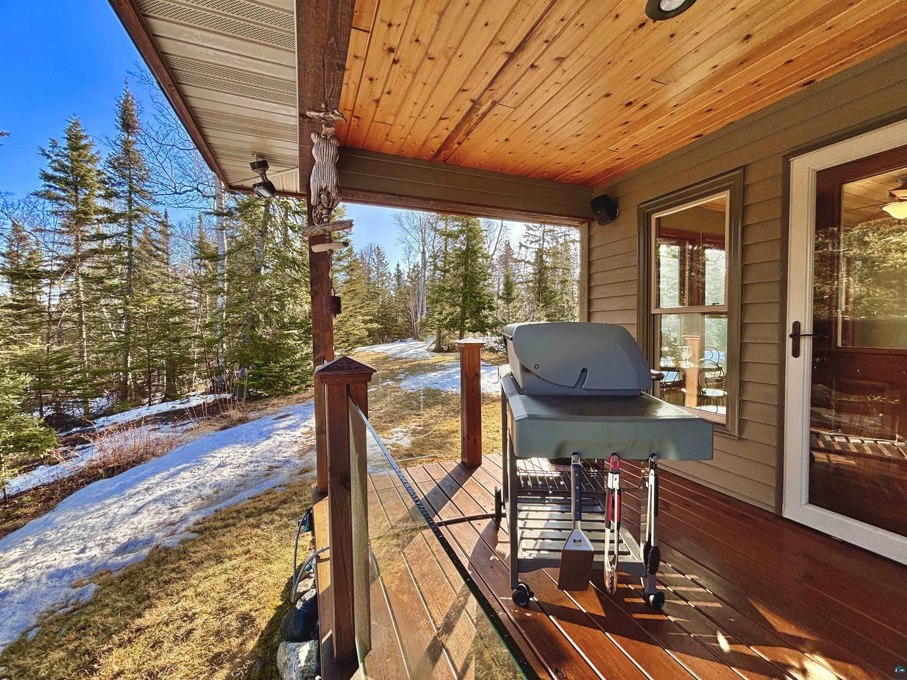 21 Turnagain Trail Lutsen, MN 55612 - Photo 18 of 77 Covered outdoor deck with glass panel railing, wood-finish flooring, and a natural wood-panel ceiling