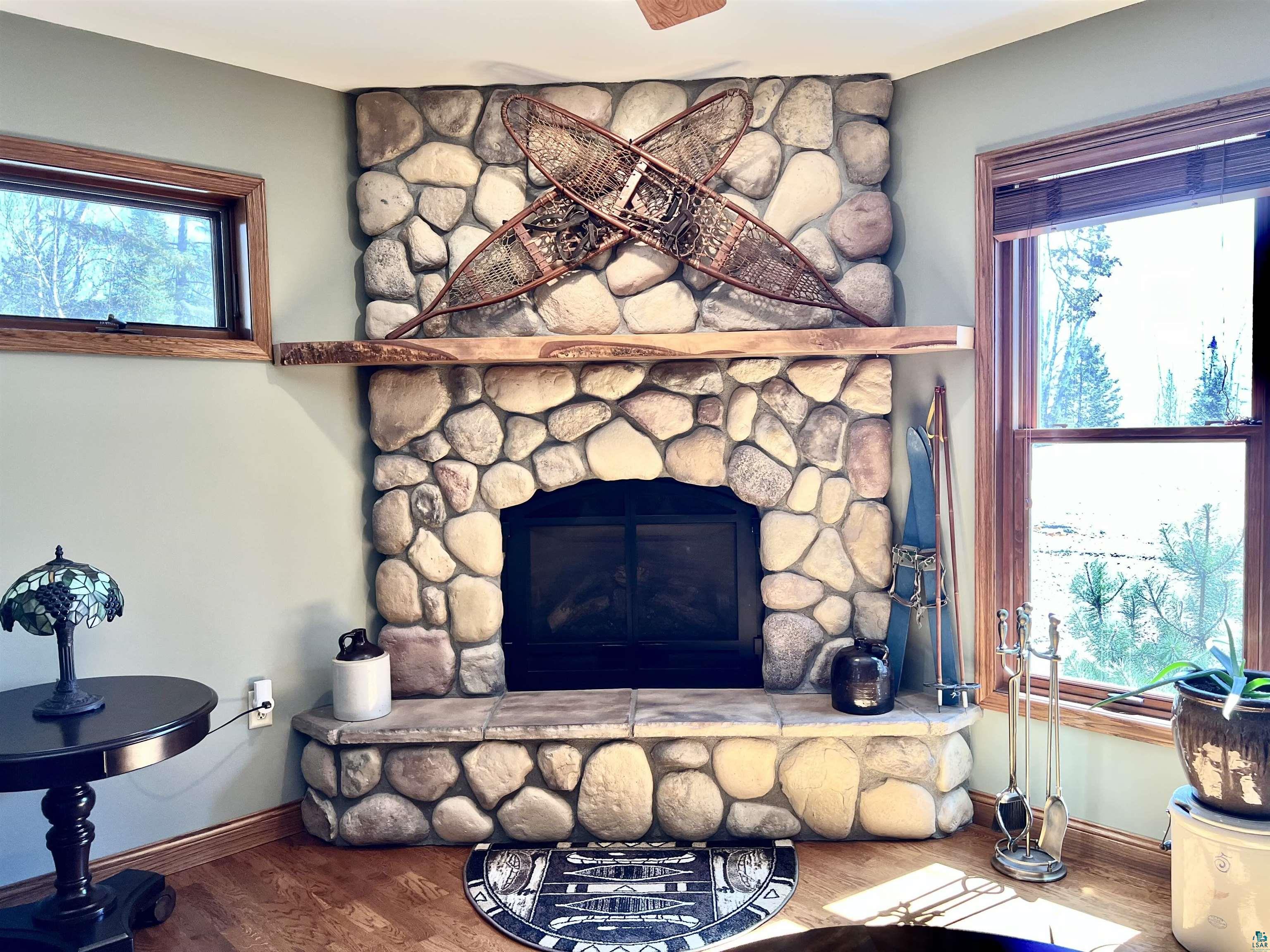 21 Turnagain Trail Lutsen, MN 55612 - Photo 19 of 77 Corner fireplace featuring a stone surround, a stone hearth, and a rustic wood mantel