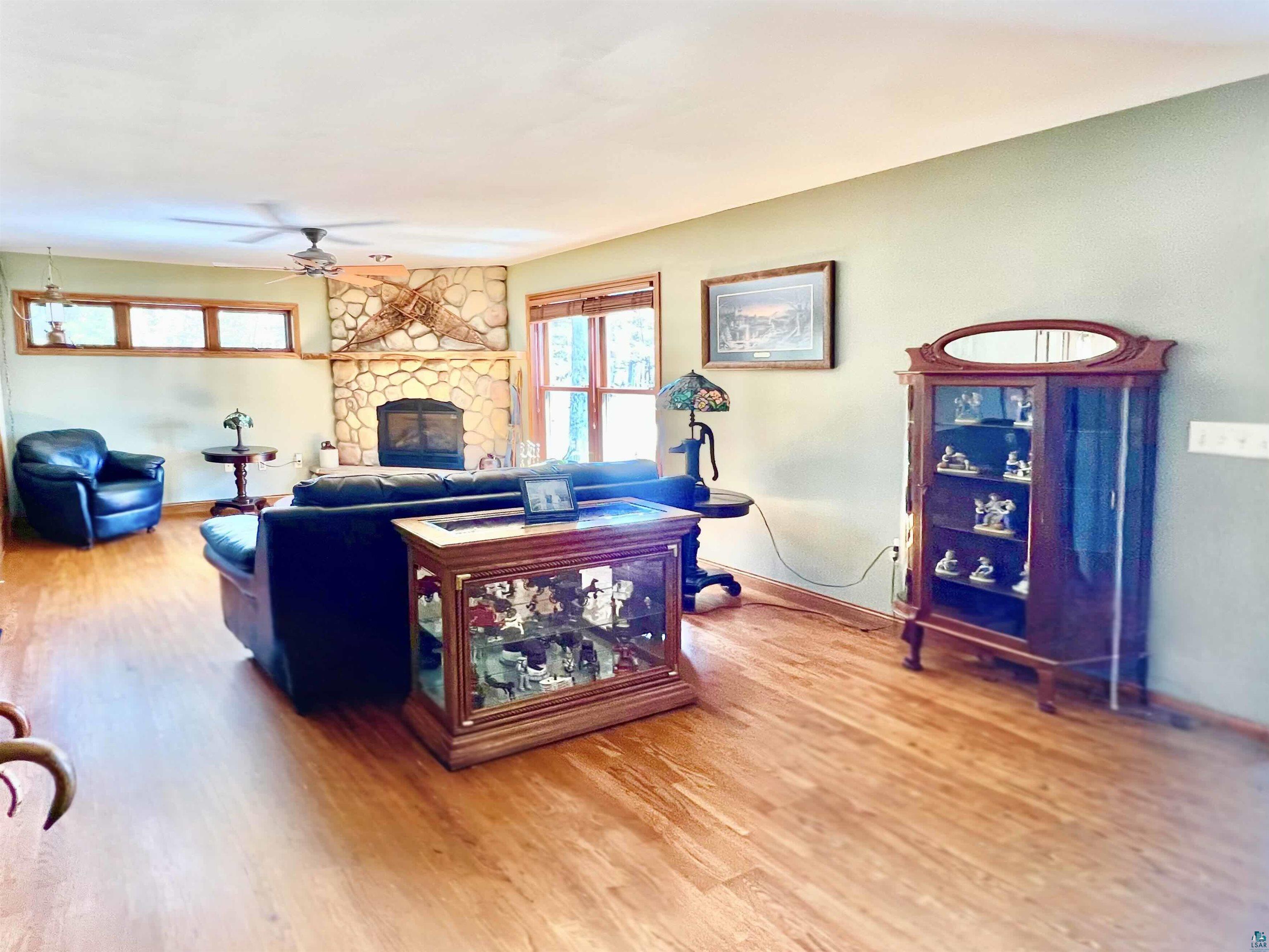 21 Turnagain Trail Lutsen, MN 55612 - Photo 21 of 77 Spacious living area featuring wood-finish flooring, a prominent stone fireplace, and wood-trimmed windows