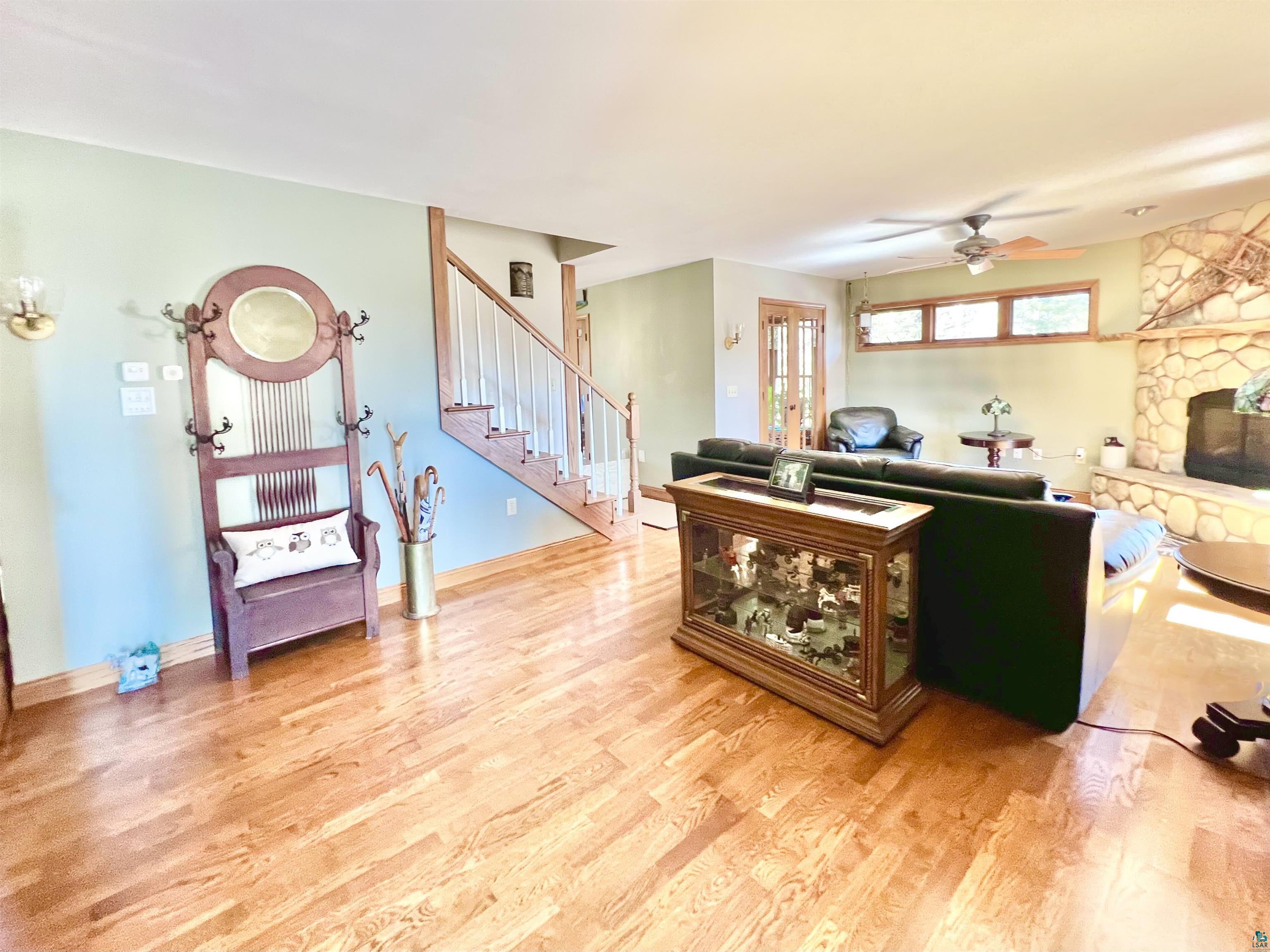 21 Turnagain Trail Lutsen, MN 55612 - Photo 22 of 77 Spacious living area featuring light wood-finish flooring, a stone-faced fireplace, a ceiling fan, and a light-toned wall color