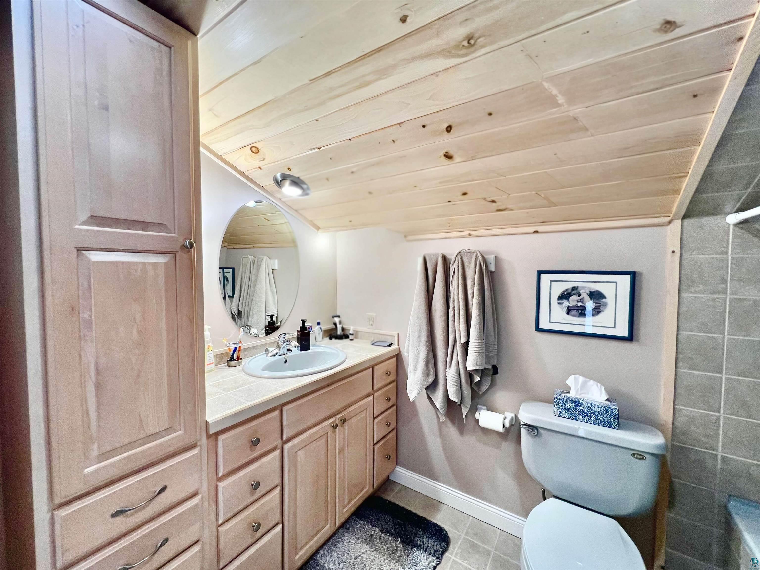 21 Turnagain Trail Lutsen, MN 55612 - Photo 36 of 77 Bathroom featuring light wood-finish planked ceiling, a vanity with light wood-finish cabinetry, a large oval mirror, and an integrated basin sink
