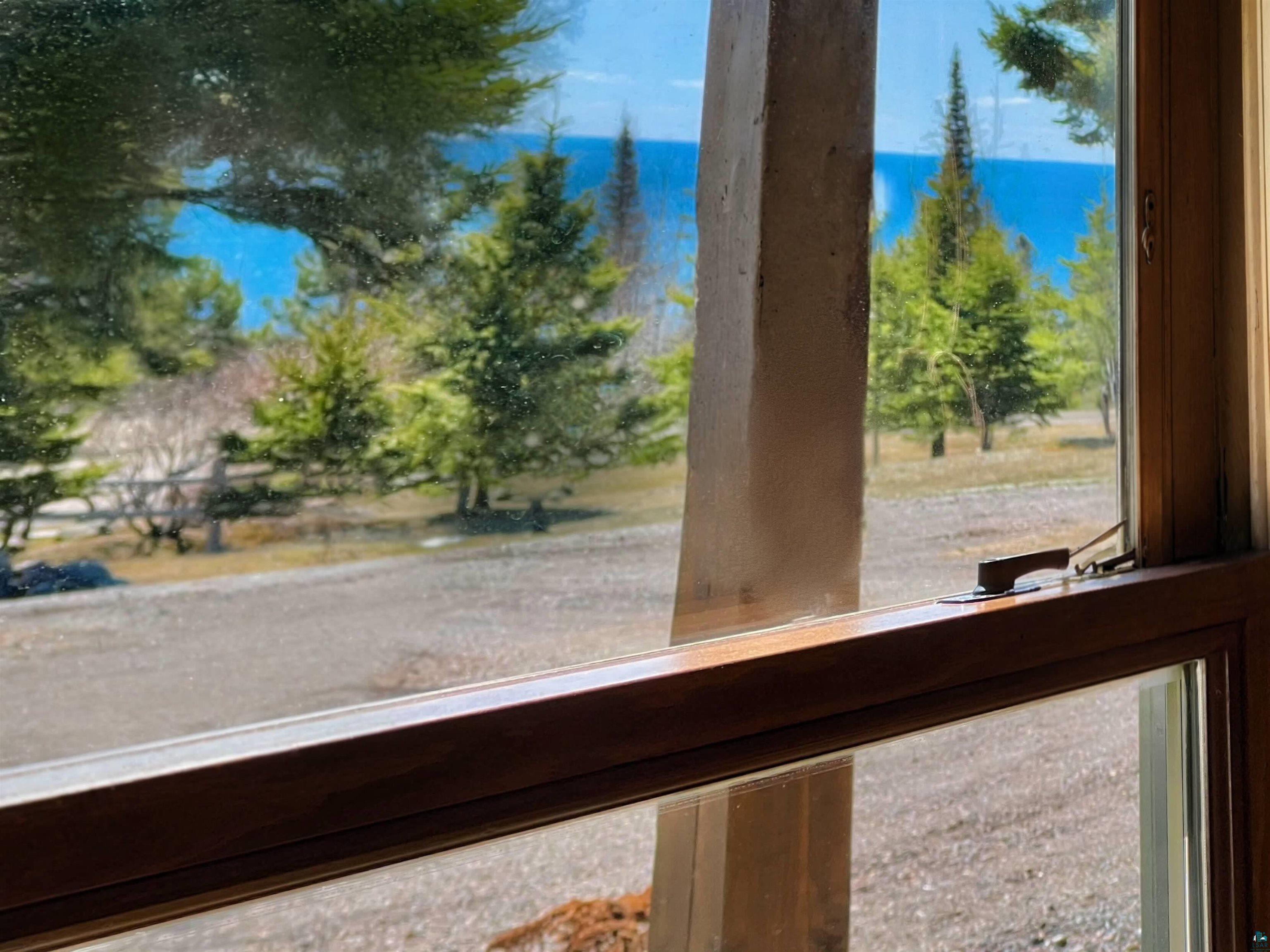21 Turnagain Trail Lutsen, MN 55612 - Photo 5 of 77 Wood-framed window featuring a brass latch, offering a broad perspective of an outdoor landscape with a water body in the background