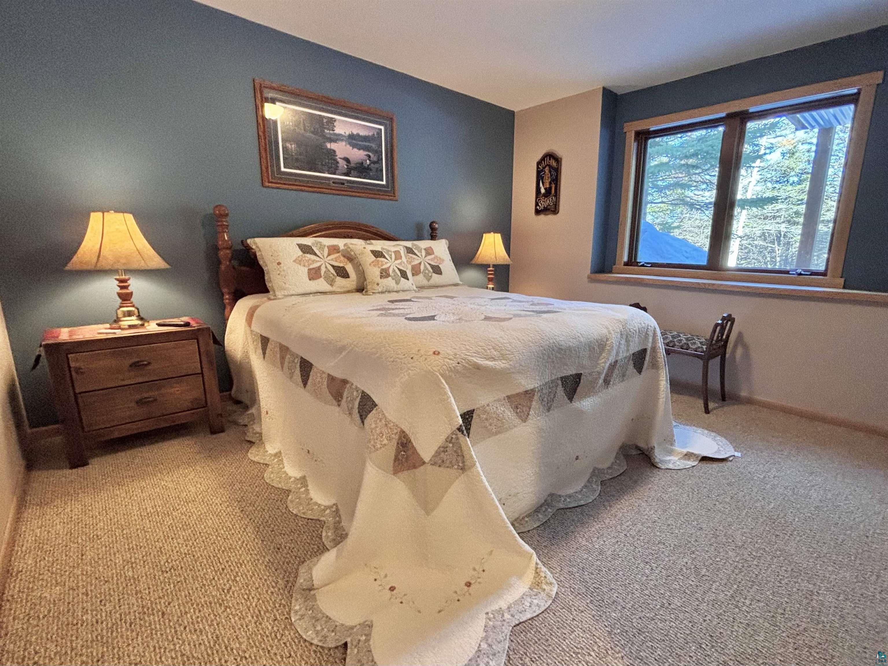 21 Turnagain Trail Lutsen, MN 55612 - Photo 57 of 77 Bedroom featuring a picture window with wood trim, wall-to-wall carpeting, and a two-tone wall finish