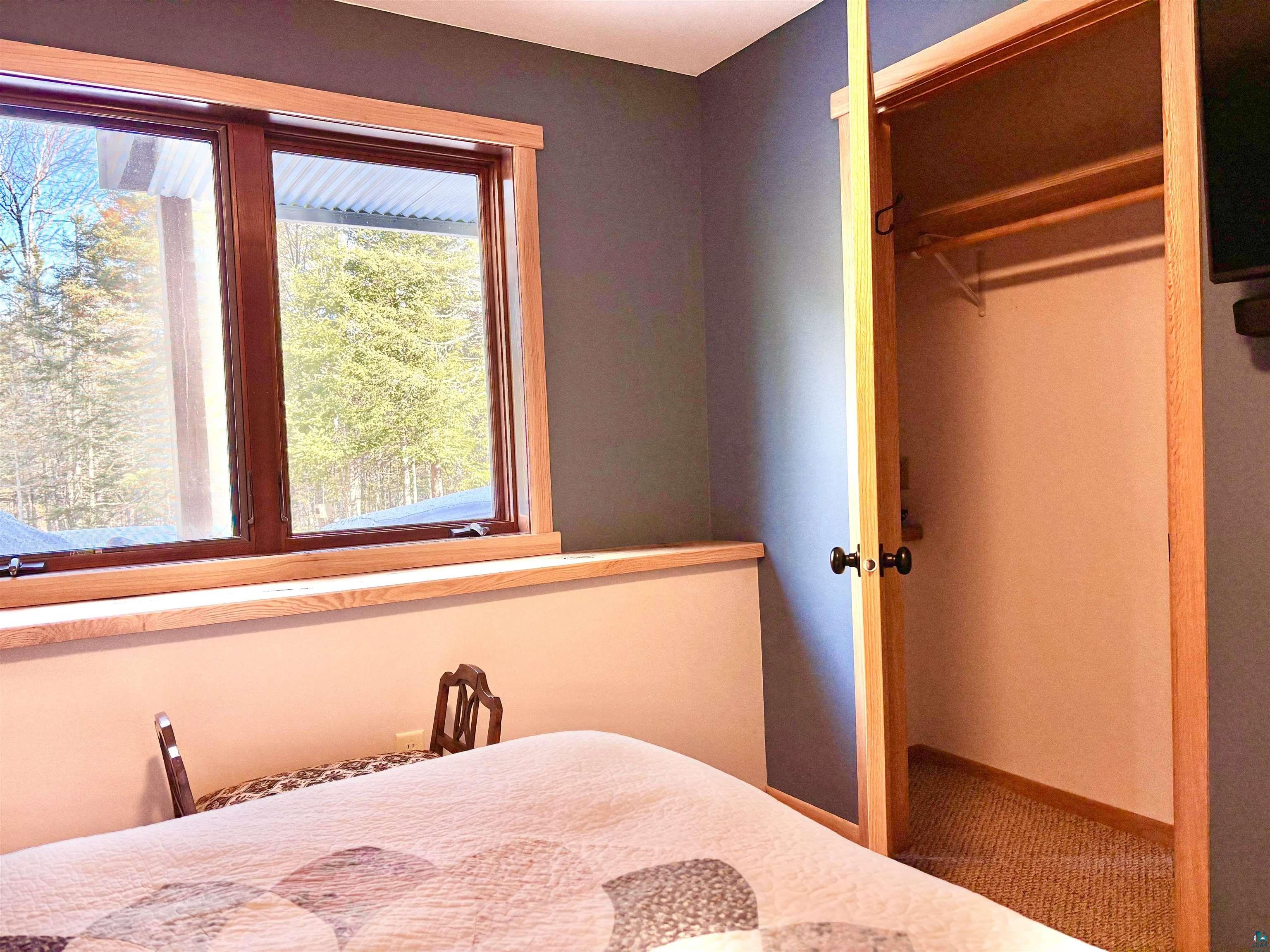 21 Turnagain Trail Lutsen, MN 55612 - Photo 59 of 77 Dual casement windows with natural wood trim, a built-in window ledge, a closet with a natural wood frame, and a wall-mounted built-in media shelf