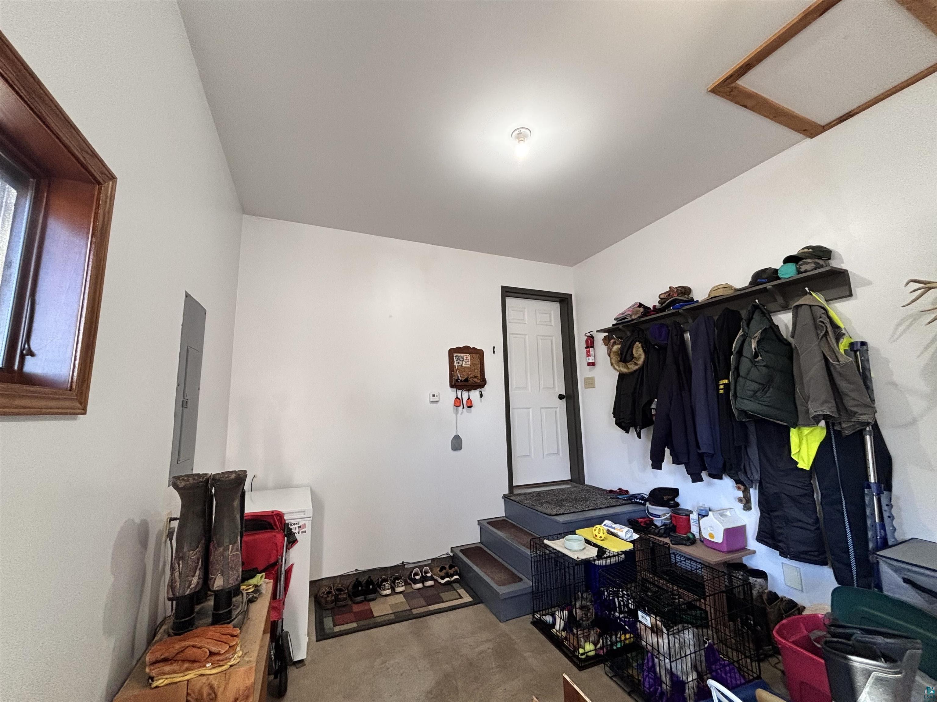 21 Turnagain Trail Lutsen, MN 55612 - Photo 62 of 77 Utility room with vaulted ceiling, a single window with wood trim, and a white interior door with dark hardware