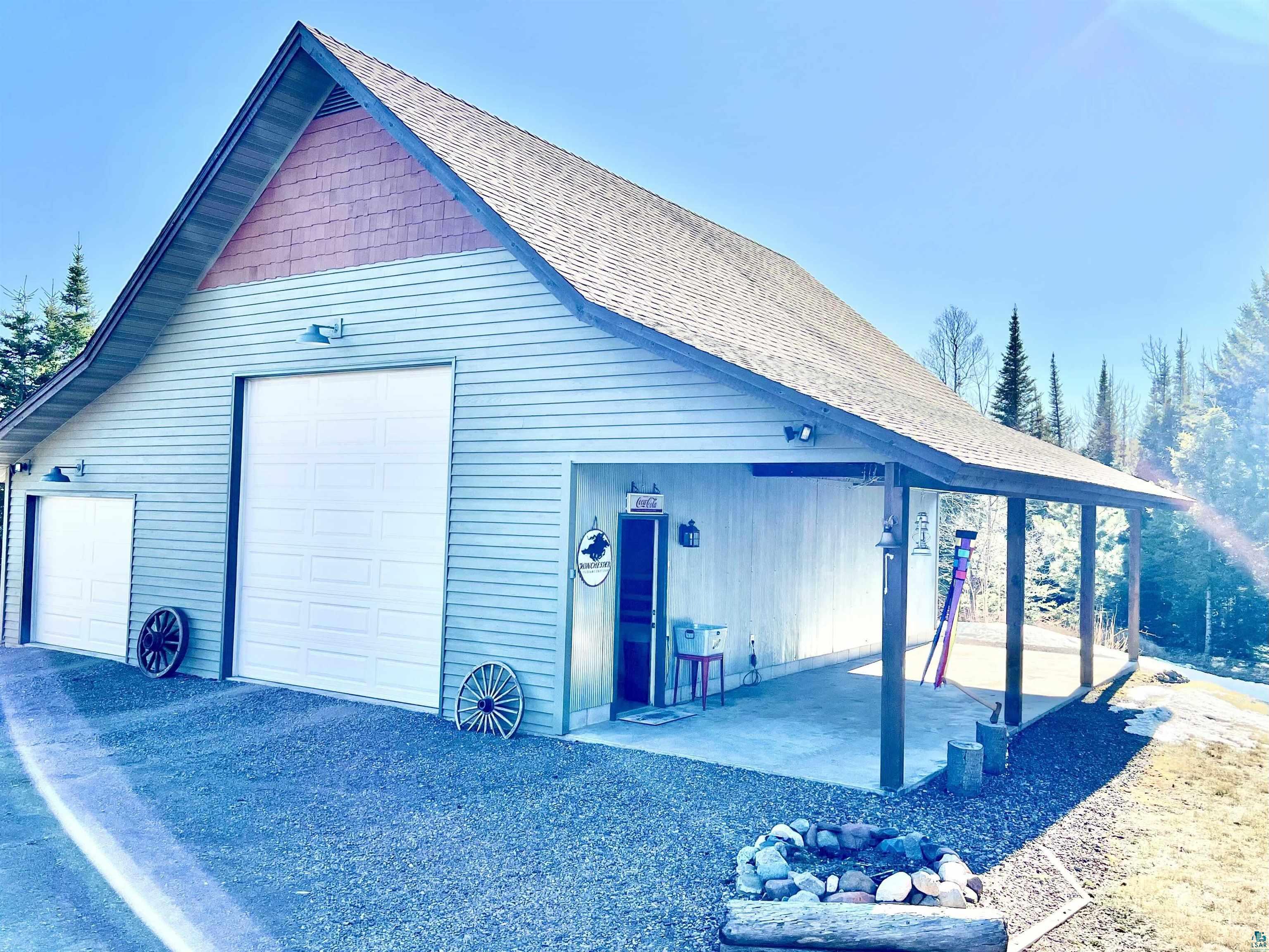 21 Turnagain Trail Lutsen, MN 55612 - Photo 73 of 77 Detached outbuilding featuring light blue siding with red shingle accents, a pitched roof, and two garage doors of varying sizes