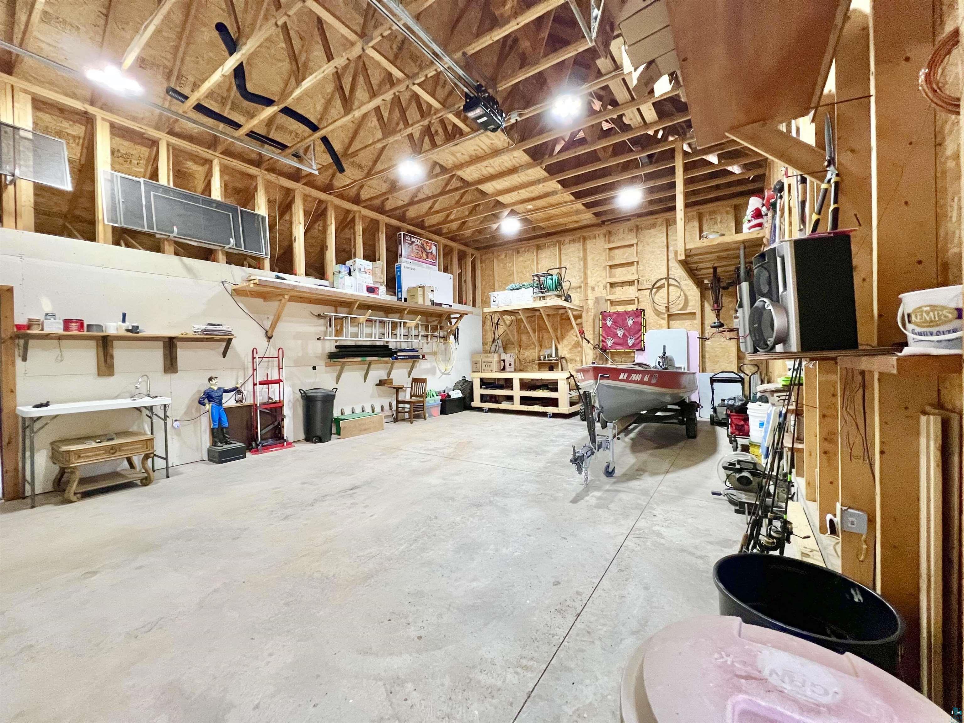 21 Turnagain Trail Lutsen, MN 55612 - Photo 74 of 77 Spacious garage featuring wood-frame construction, exposed rafters, concrete flooring, and ample overhead lighting