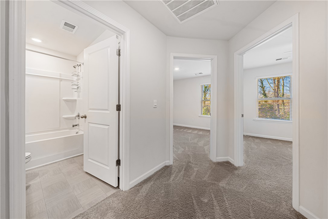 404 Oakmont Valley Trail Seneca, SC 29678 - Photo 23 of 44 This interior hallway offers a clean aesthetic, connecting bright, carpeted rooms with serene outdoor views.