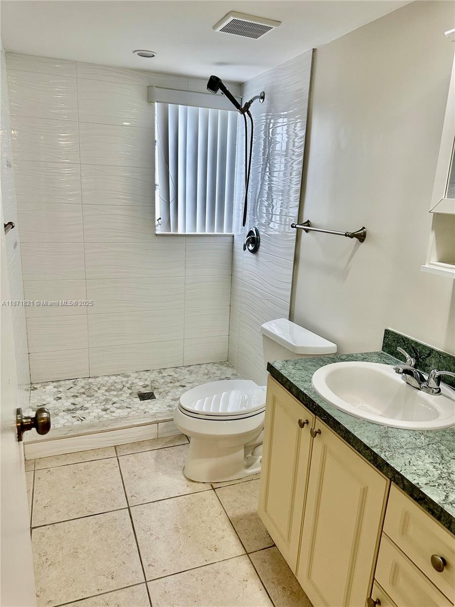 300 Northeast 12th Avenue, Unit 101 Hallandale Beach, FL 33009 - Photo 14 of 23 a bathroom with a granite countertop sink a toilet and a mirror