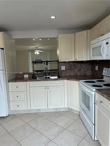 a kitchen with granite countertop white cabinets and white appliances