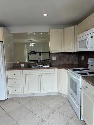 a kitchen with granite countertop white cabinets and white appliances