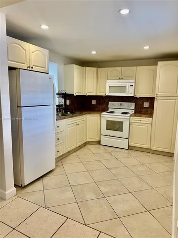 a kitchen with a refrigerator a stove top oven and a sink with wooden floor
