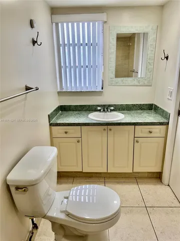 a bathroom with a granite countertop toilet a sink and a mirror