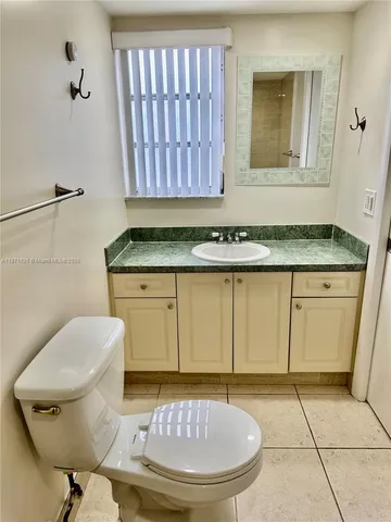 a bathroom with a granite countertop toilet a sink and a mirror