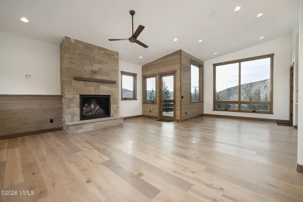an empty room with windows fireplace and wooden floor