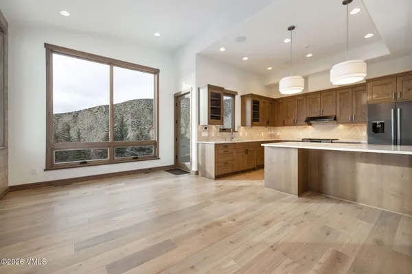 a large kitchen with stainless steel appliances granite countertop a stove top oven a sink dishwasher and a refrigerator with wooden floor