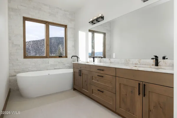 a bathroom with a tub double sink window and mirror