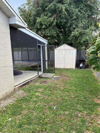 a view of a small house with a small yard and a large tree