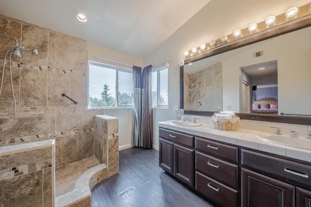 a en suite bathroom with a granite countertop tub a mirror and a shower