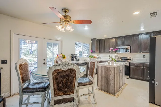 a very nice looking dining room with kitchen island furniture a refrigerator and a chandelier