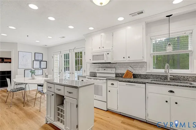 a kitchen with white cabinets sink and window