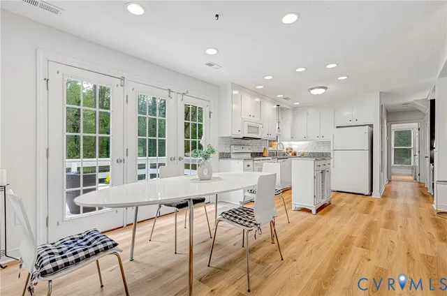 a kitchen with stainless steel appliances kitchen island granite countertop a refrigerator a stove a sink dishwasher with a dining table and chairs with wooden floor