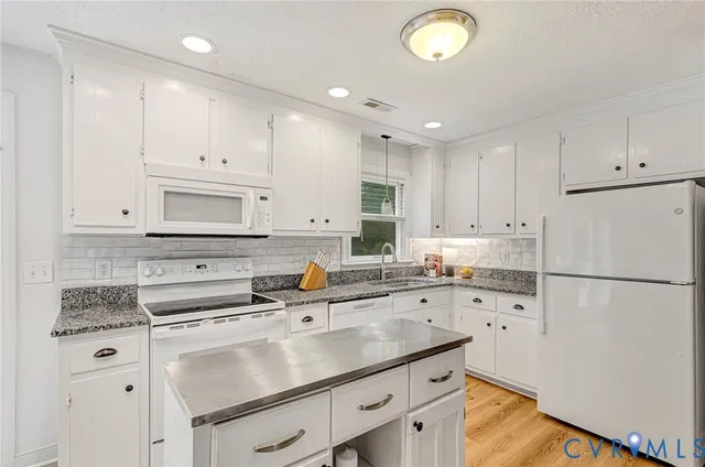a kitchen with granite countertop a sink cabinets and refrigerator