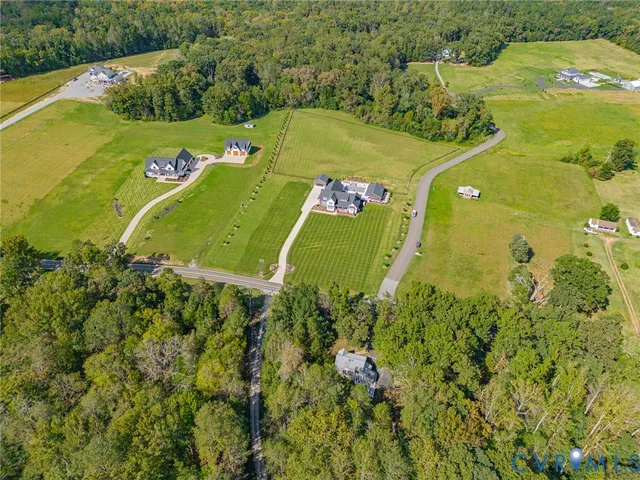 an aerial view of a residential houses with outdoor space and trees all around