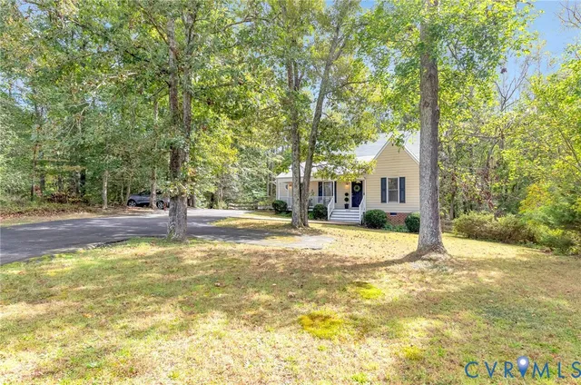 a view of a white house with a large tree and plants
