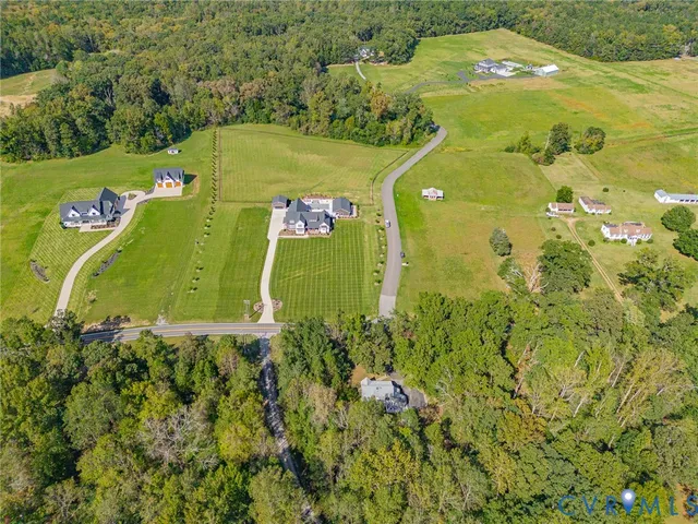 an aerial view of a residential houses with outdoor space and trees all around