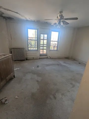 an empty room with windows and chandelier fan