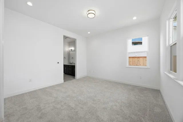 an empty room with a bathroom and windows