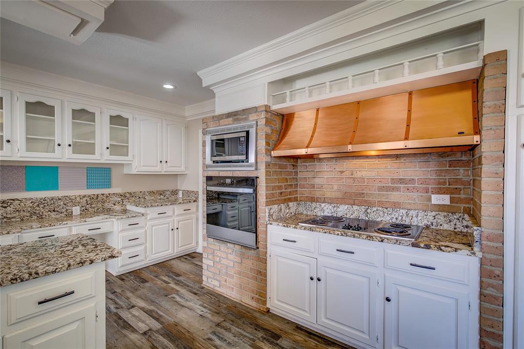 7359 Highway 154 Sulphur Springs, TX 75482 - Photo 14 of 40 Kitchen has electric cooktop with copper vent hood and storage above; wall oven and microwave, all built into brick
