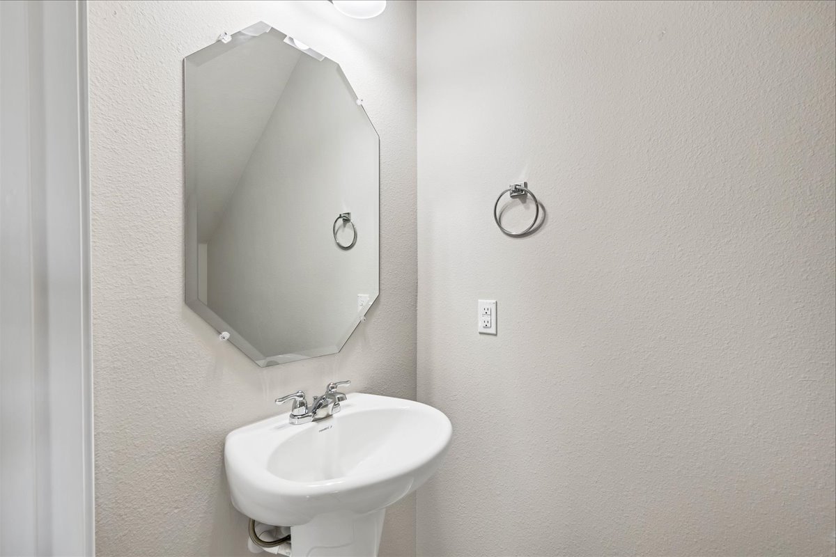 1202 Garland Road Georgetown, TX 78626 - Photo 17 of 28 Pedestal sink with chrome faucet, octagonal mirror, and light-colored wall finish