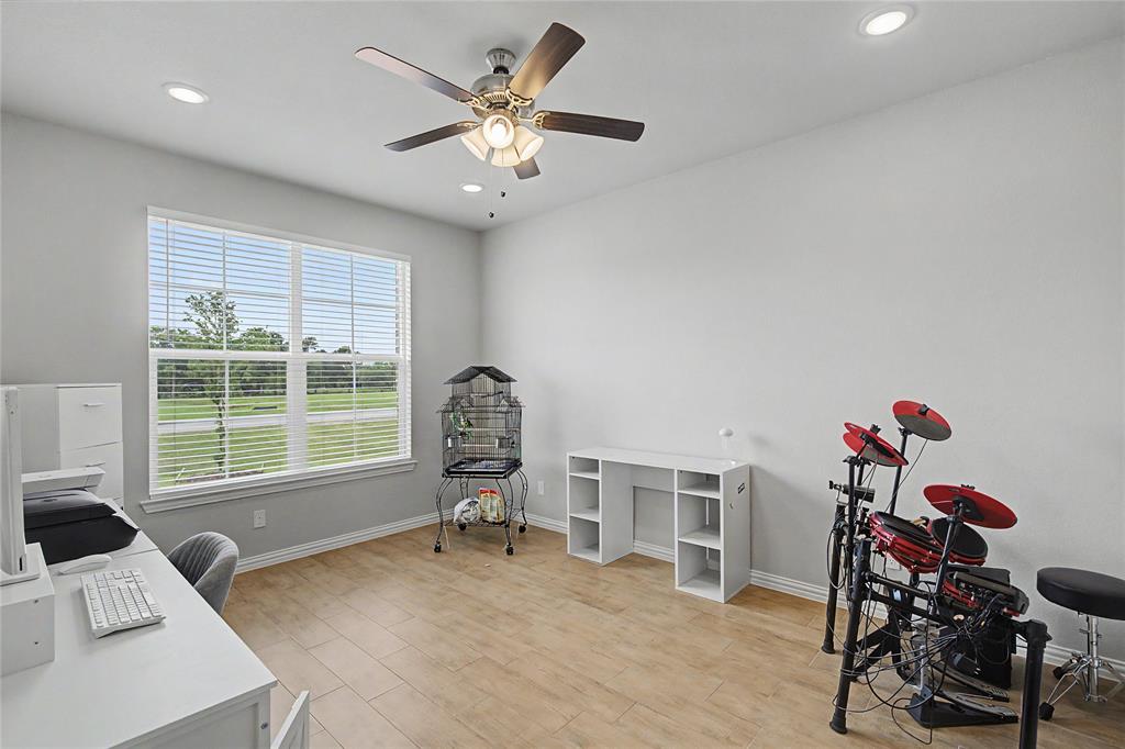 185 Chester Road Springtown, TX 76082 - Photo 31 of 40 Spacious room featuring wood-finish flooring, a large window with horizontal blinds, and a ceiling fan with integrated lighting