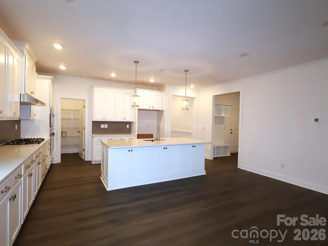 a kitchen with granite countertop white cabinets and a wooden floor