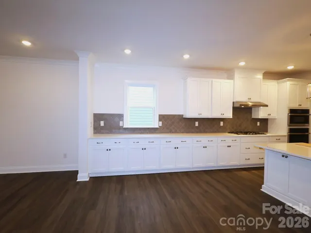 an empty room with wooden floor fireplace and windows