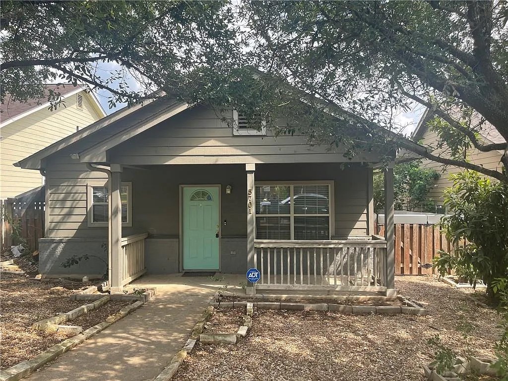 Single-story residence featuring a covered front porch, a bright teal entry door with an arched window, and horizontal siding