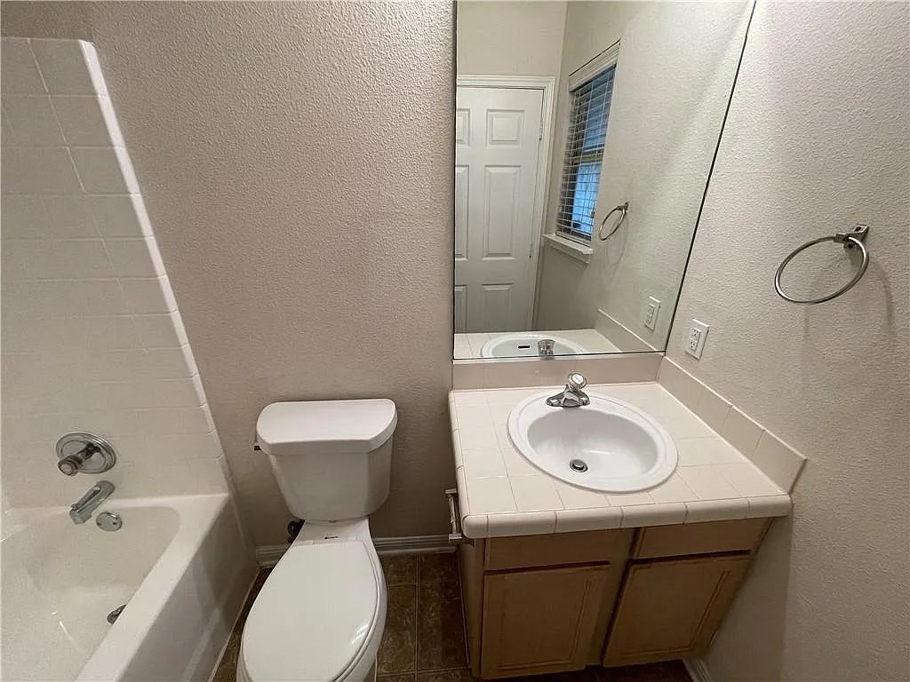 5701 Signal Point Austin, TX 78724 - Photo 11 of 12 Bathroom featuring a single vanity with an integrated sink, tile countertop, and wood-finish cabinetry
