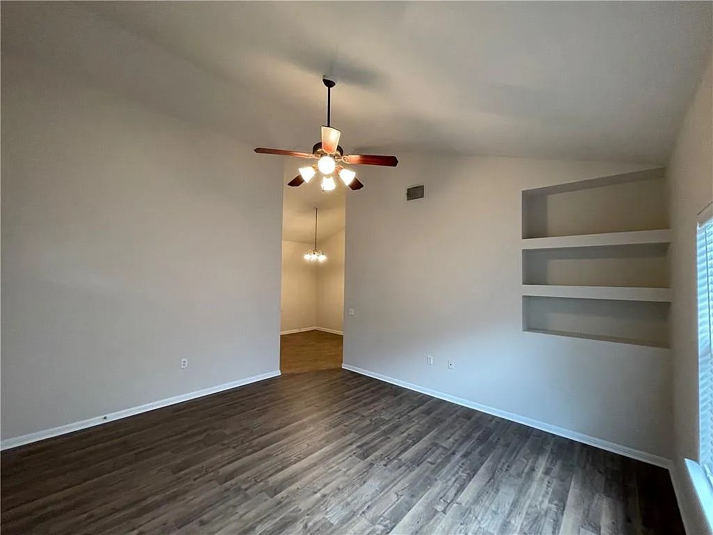5701 Signal Point Austin, TX 78724 - Photo 5 of 12 Living area featuring wood-finish flooring, a ceiling fan with integrated lighting, built-in recessed shelving, and a prominent window with horizontal blinds