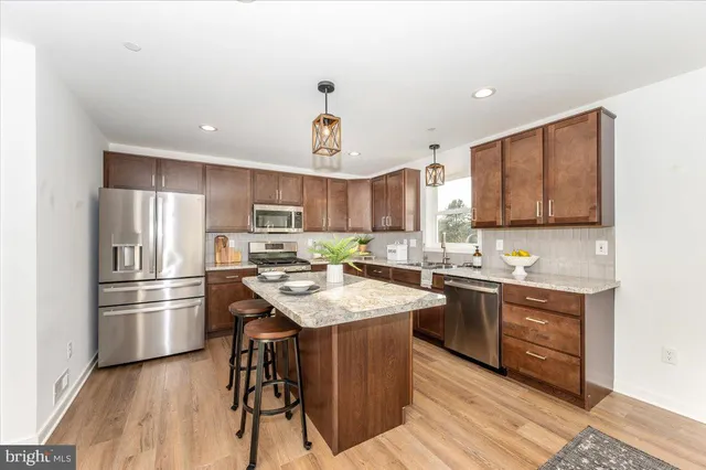 a kitchen with stainless steel appliances granite countertop a stove top oven a sink dishwasher a dining table and chairs with wooden floor