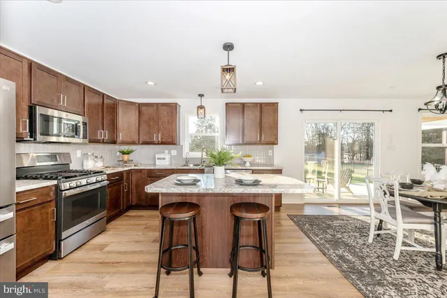 a kitchen with stainless steel appliances granite countertop wooden cabinets a sink and dishwasher with wooden floor