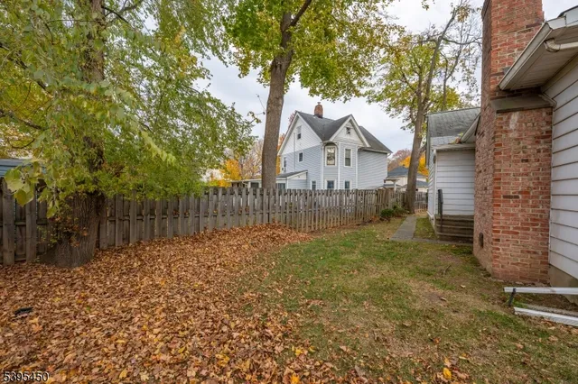 a view of a house with a large tree and wooden fence