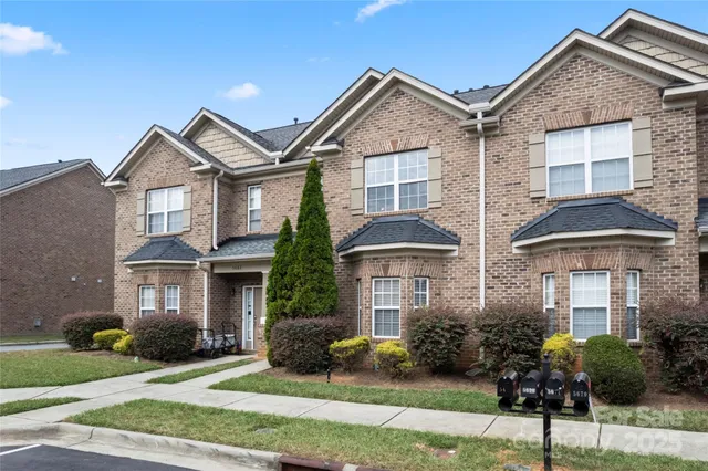 a front view of a house with a yard and potted plants