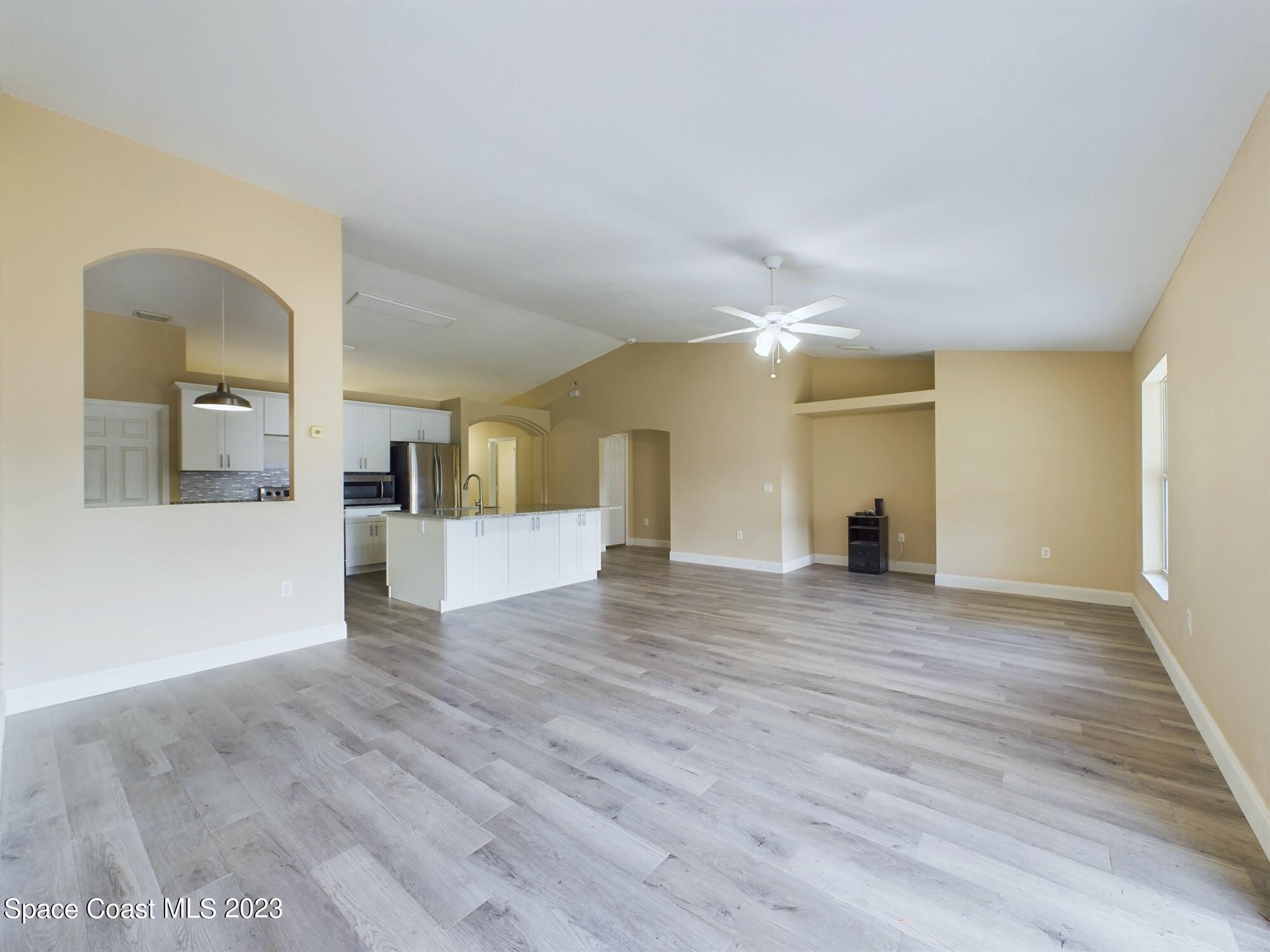 248 Benchor Road Northwest Palm Bay, FL 32907 - Photo 11 of 31 a view of empty room with wooden floor and kitchen view