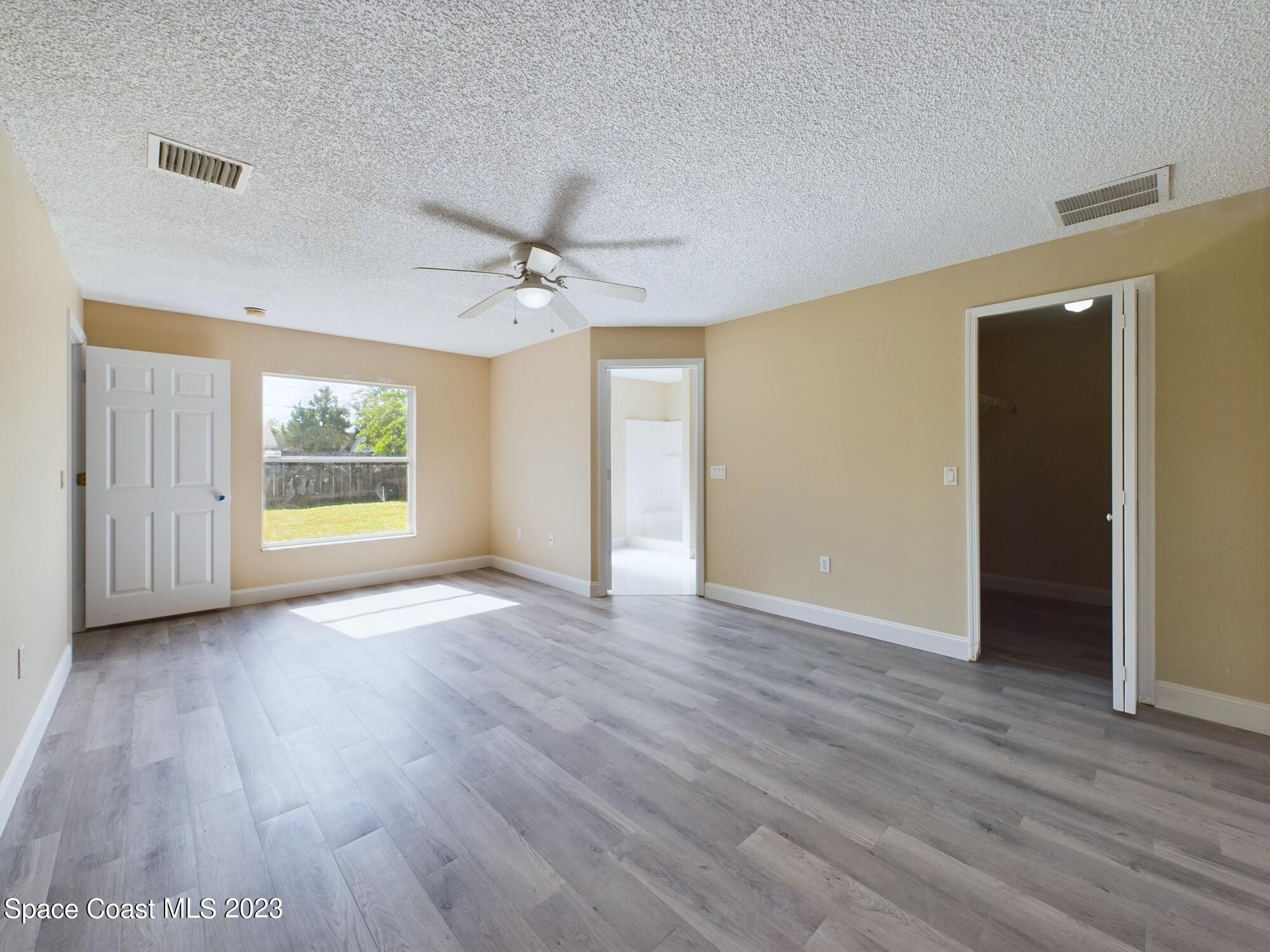 248 Benchor Road Northwest Palm Bay, FL 32907 - Photo 13 of 31 a view of an empty room with a window and wooden floor